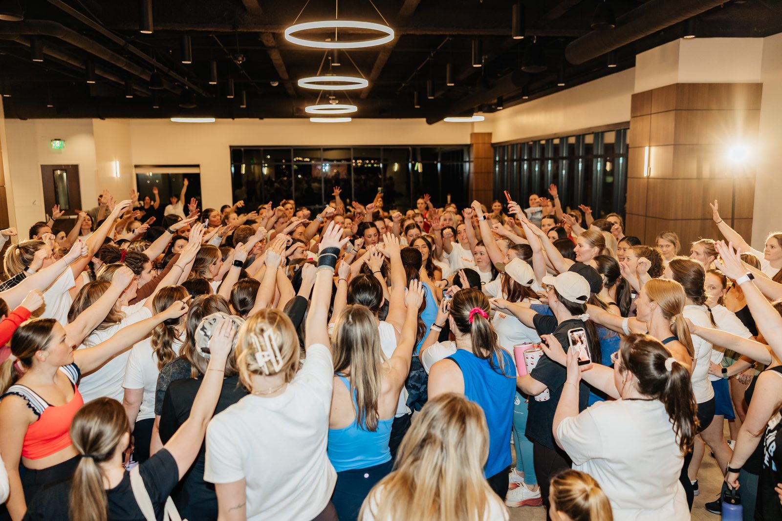 A room full of Mamele members with their hands in the air together at an in-person event.