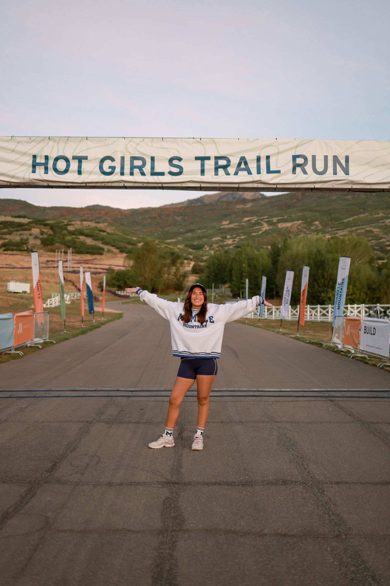 Andrea, arms spread wide on the Mamele Mountains start-line road at dawn.