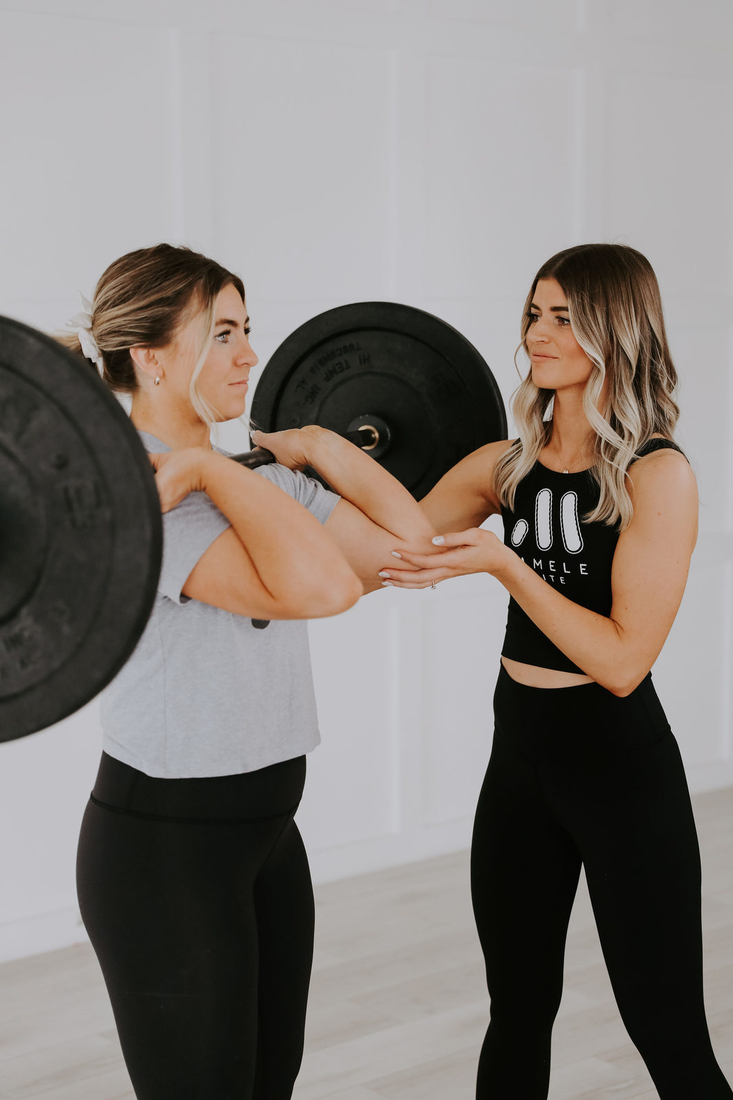 A Mamele coach spotting a member hands-on through a loaded barbell lift.